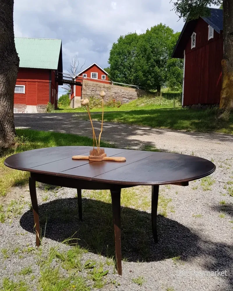 Ovalt matbord i mörkt trä med iläggsskivor